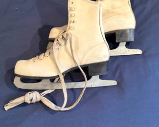 These are vintage white leather women's figure skates, featuring classic lace-up designs, toe picks, and riveted steel blades.