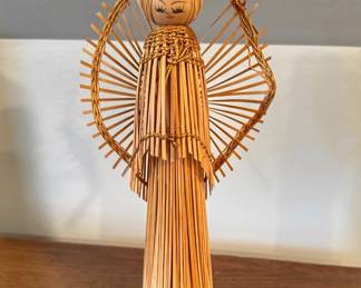 This is a vintage handmade straw and wood angel figurine featuring a painted wooden bead face, delicate fan-shaped stick wings, and metallic gold cord trim.