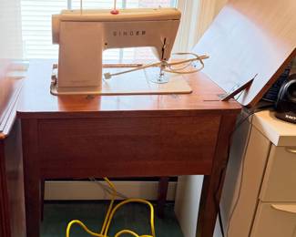 The is a vintage Singer sewing machine housed inside a wooden drop-leaf console cabinet table.