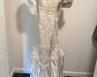This vintage satin and lace wedding gown features puff sleeves, an ornate beaded sweetheart neckline, and intricate pearl-and-sequin applique panels.