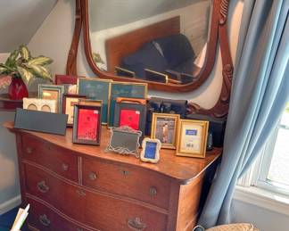 This is an early 20th-century American quarter-sawn oak serpentine-front dresser featuring an ornate, attached swivel mirror and original batwing or teardrop pulls.