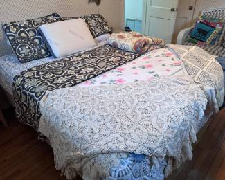 queen bed with bedframe, various blankets and comforter sets on bed