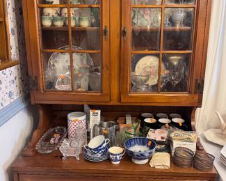 dish cabinet with various wine glasses, tea sets and decorative plates