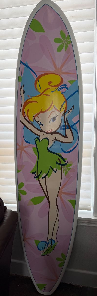 Disney Tinker Bell surfboard. Featuring a double sided Tinker Bell airbrush design with leash, and 3 FCS fins. 7’0 squash tail. Designed by Surftech founder, Randy French. Only 1 Tinker Bell surfboard was made per Disney store. This rare and highly collectible Disney surfboard has never been ridden. Excellent all original condition.