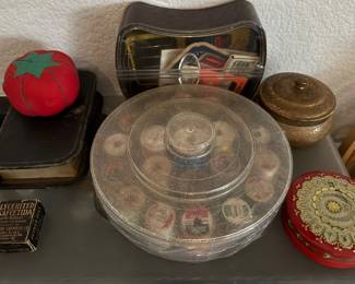 Wooden spools of thread, tin filled with pins, case full of vintage bobbins, tin full of sewing needles…..