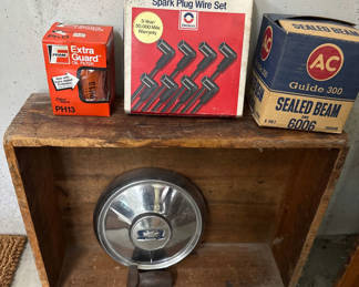 Lot 6: Oil filter box, spark plug wire set box, sealed beam headlight box, Chevrolet hubcap, and hammer