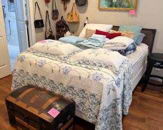 Queen bed with comforter set pillows, and sheet sheets and antique trunk