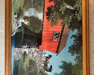 Framed Covered Bridge Print — Framed lithograph-style print depicting a red covered bridge over a stone foundation with a horse and buggy and a child fishing at the bank. The print is behind glass in a simple light-wood frame with a gold inner trim; colors are bright with predominant red, blue and green tones. Frame shows minor surface wear and the glass appears intact; the print itself has no obvious tears or stains. A decorative, wall-ready rural scene that measures approximately as listed.