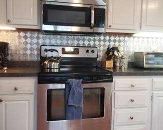 Crisp white kitchen with painted cabinets; Frigidare electric range; microwave oven