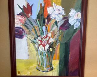 framed still-life floral painting in an impressionist or expressionist style features a vibrant bouquet of red and purple tulips and white blossoms in a clear glass vase, set against a colorful, multi-toned background with a yellow table surface.