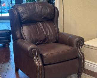 dark brown leather high-leg recliner appears to be a traditional Chippendale-style wingback reclining chair featuring brass nailhead trim and exposed wooden cabriole/ball-and-claw style feet.