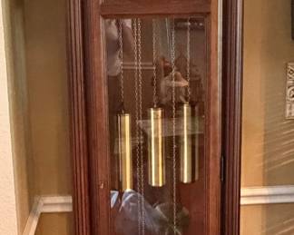 classic Howard Miller grandfather clock featuring a traditional wooden case, a moon phase dial, and polished brass weights.