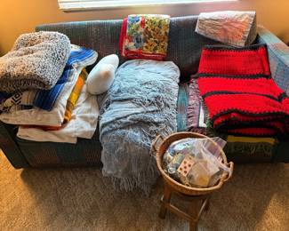 Various blankets, throws, on vintage little couch
