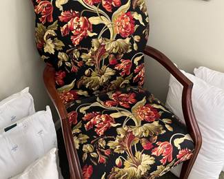 Vintage armchair with a dark wood frame, ornate carved arms, and floral upholstery.