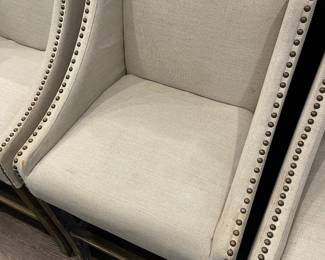 Closer view of one of the four beige upholstered counter stools by Gabby.