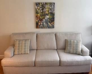 Upholstered Beige Sofa With Throw Pillows And Art Canvas