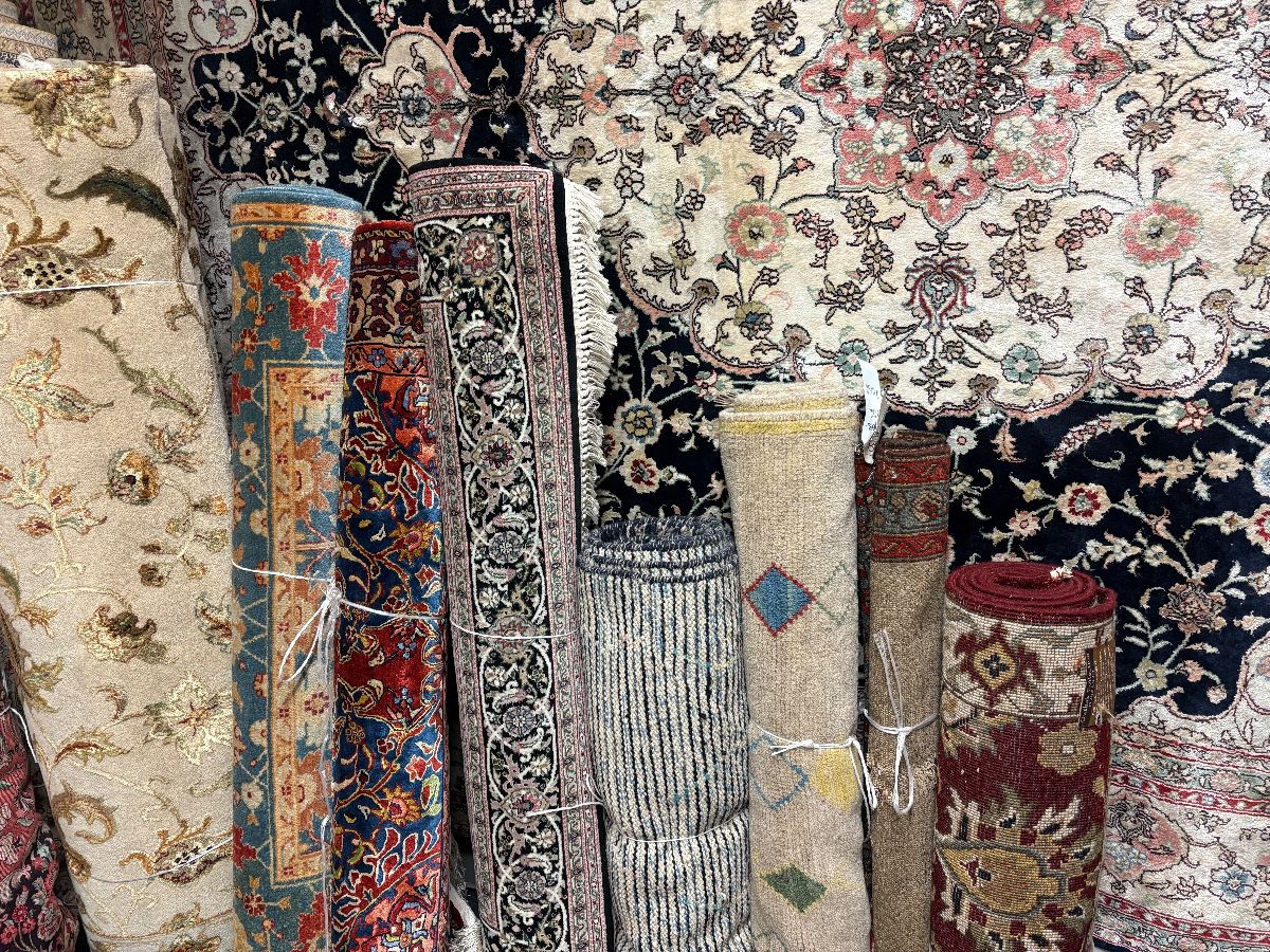 Assorted rolled rugs showcasing intricate floral and traditional designs
