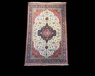 Ivory rug with burgundy and blue central medallion on dark background