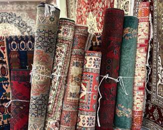 Large collection of rolled rugs featuring traditional patterns and rich colors