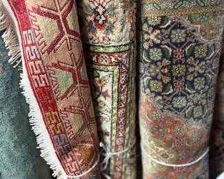 Assorted rolled rugs showcasing a variety of traditional patterns and colors