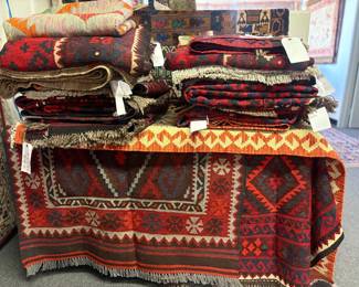Stacked collection of tribal and geometric rugs in bold red and earth tones