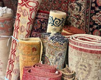 Assorted rolled rugs featuring neutral, pastel, and traditional designs