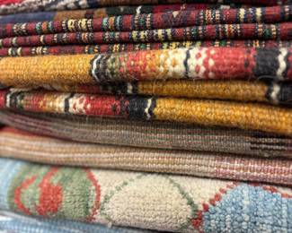 Assorted folded rugs showcasing colorful traditional patterns and textures