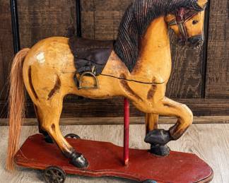 vintage wooden pull horse toy mounted on a wheeled platform.