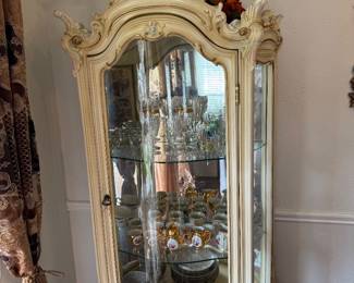 Elegant Curio / China Cabinet – Ornate Cream Finish Description: Beautiful cream-colored china cabinet with glass doors, mirrored back, glass shelves, and ornate detailing. Perfect for displaying china, crystal, collectibles, or home décor. Features: * Mirrored interior * Glass shelves * Elegant carved details * Cream finish with subtle gold accents. Light included inside ceiling up top.