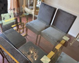 Modern Glass Dining Table with 6 Chairs – Gold Base Beautiful contemporary dining set featuring a thick tempered glass tabletop with a gold geometric metal base and six upholstered gray dining chairs. Great condition and perfect for a modern dining room. * Seats 6 comfortably * Glass top * Gold metal base * Six upholstered chairs included