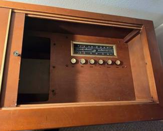 Close-up of the built-in AM/FM radio controls on a vintage wood stereo console. Classic mid-century audio equipment featuring original tuning controls and timeless craftsmanship, available at this Tavares, Florida estate sale hosted by Kinfolk Estate Sales.