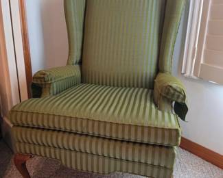 Traditional upholstered wingback chair with green striped fabric, carved wooden Queen Anne-style legs, and classic English-inspired design. Perfect for traditional, Colonial, vintage, or cottage-style home décor. Available at the Tavares, FL estate sale hosted by Kinfolk Estate Sales.