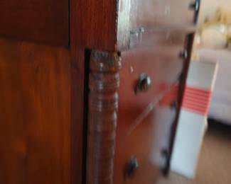 Detailed view of an antique chest of drawers featuring beautifully turned columns, aged wood patina, and classic handcrafted construction. Discover authentic antique furniture and timeless estate treasures at this Tavares, FL estate sale by Kinfolk Estate Sales.