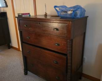 Antique solid wood chest of drawers featuring hand-crafted construction, turned columns, original hardware, and timeless craftsmanship. A beautiful early furniture piece available at this Tavares, Florida estate sale hosted by Kinfolk Estate Sales.