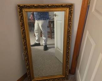Large decorative wall mirror featuring an ornate gold-tone frame with traditional styling. A beautiful accent for an entryway, bedroom, living room, or dining room, available at this Tavares, Florida estate sale hosted by Kinfolk Estate Sales.