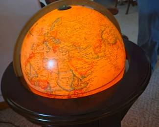 Vintage illuminated world globe displayed on a wooden accent table. A unique decorative piece for a home office, library, or study, available at this Tavares, Florida estate sale hosted by Kinfolk Estate Sales.