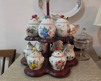 Collectible hand-painted ceramic kitchen canister set with fruit motifs displayed on a wooden carousel stand. Quality kitchen décor and decorative collectibles at this Tavares, FL estate sale.