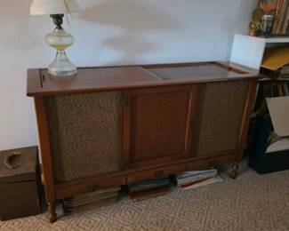 Vintage wood stereo console featuring a built-in AM/FM radio, record player, and woven speaker panels. A beautiful mid-century entertainment center and collectible audio piece available at this Tavares, Florida estate sale hosted by Kinfolk Estate Sales.