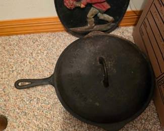 Vintage cast iron Dutch oven with lid and collectible cast iron cookware displayed alongside decorative cast iron wall art. Durable kitchen essentials and vintage collectibles available at this Tavares, Florida estate sale hosted by Kinfolk Estate Sales.