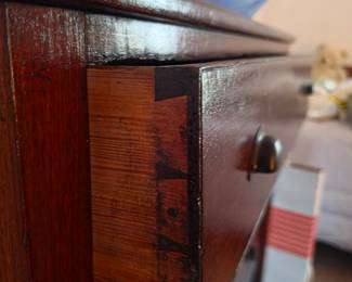 Close-up of hand-cut dovetail drawer joinery on an antique solid wood chest of drawers, showcasing exceptional craftsmanship and early furniture construction. A remarkable antique furniture find at this Tavares, Florida estate sale hosted by Kinfolk Estate Sales.