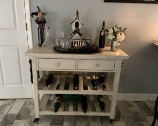 Wine Rack Cabinet with A Lighted Church, Floral Arrangement, and A Wine Jacket “Jester”