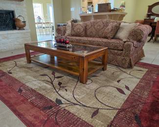 Large area rug, a glass top coffee table, and a sleeper sofa. All are in excellent condition