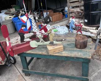4 folkart whirligigs and a rustic green sturdy table.