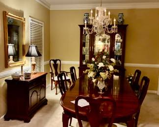Dining room set features an elegant oval extension table and matching splat-back chairs with cream- upholstered seats , matching sideboard and china cabinet