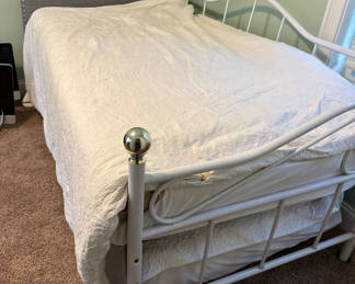 Lot 23: White metal trundle bed frame with upholstered headboard, white quilt, and floral-pattern mattress