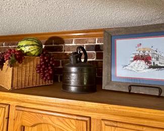 Left to Right: Antique Cast Iron Pot with Wire Bail Handle. $35. Wicker Fruit Basket with Faux Fruit. $15. Antique Juwel No. 2 Kerosene Can. $35. Framed "Delta Queen" Steamboat Needlepoint Framed Artwork. $35