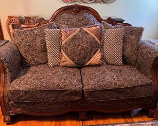 Rococo/Baroque style upholstered loveseat or settee. Arched camelback wood frame with carved scrolling accents, rolled arms with a brass nailhead trim border, and rich chocolate and tan tapestry upholstery with a heavy paisley and brocade pattern. Approx. 72w x 47h. $200.