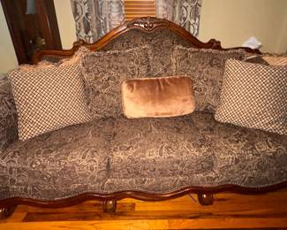 Rococo/Baroque style upholstered sofa. Arched camelback wood frame with carved scrolling accents, rolled arms with a brass nailhead trim border, and rich chocolate and tan tapestry upholstery with a heavy paisley and brocade pattern. Approx. 88 x 47h. $300.00
