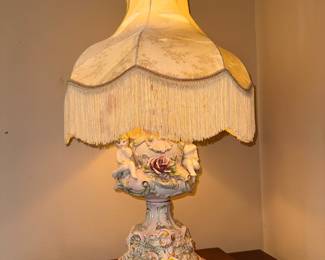 Vintage Italian Capodimonte-style porcelain cherub table lamp. Approx. 25h x 10w. (era 1950s-1970s).  The exterior shade is in good condition but there is some tearing of the inner liner near the socket. Approx. 25h x 10w.$150