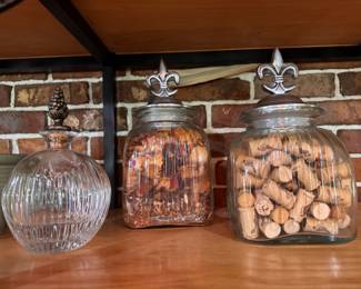 Pinecone Top Ribbed Glass Decanter/Bottle $10. Fleur-de-Lis Ribbed Glass Canisters. Smaller one filled with potpourri mix. $10. Larger filled with wine corks. $10.